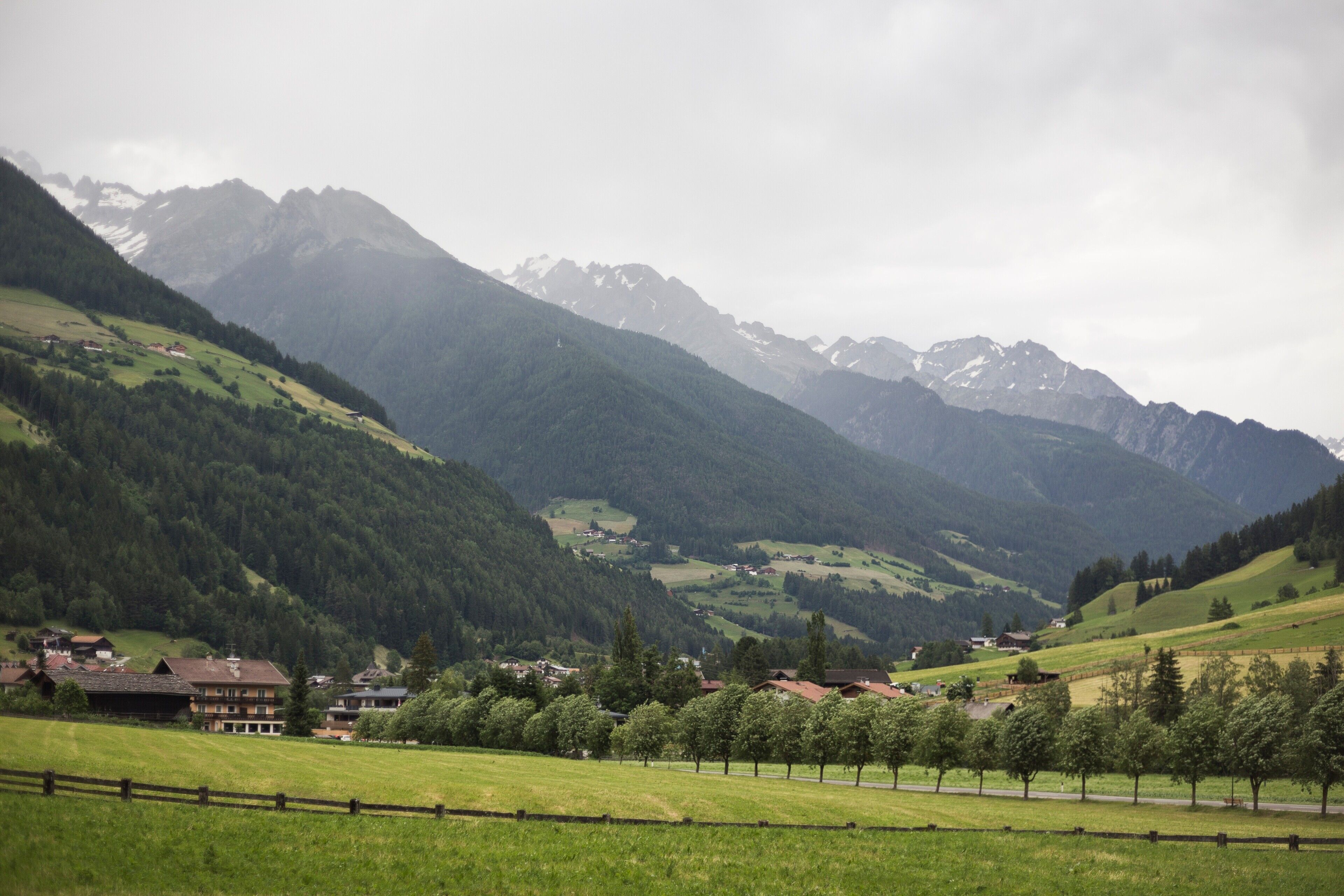 Paisaje rural con una cordillera, una carretera y algunos edificios.