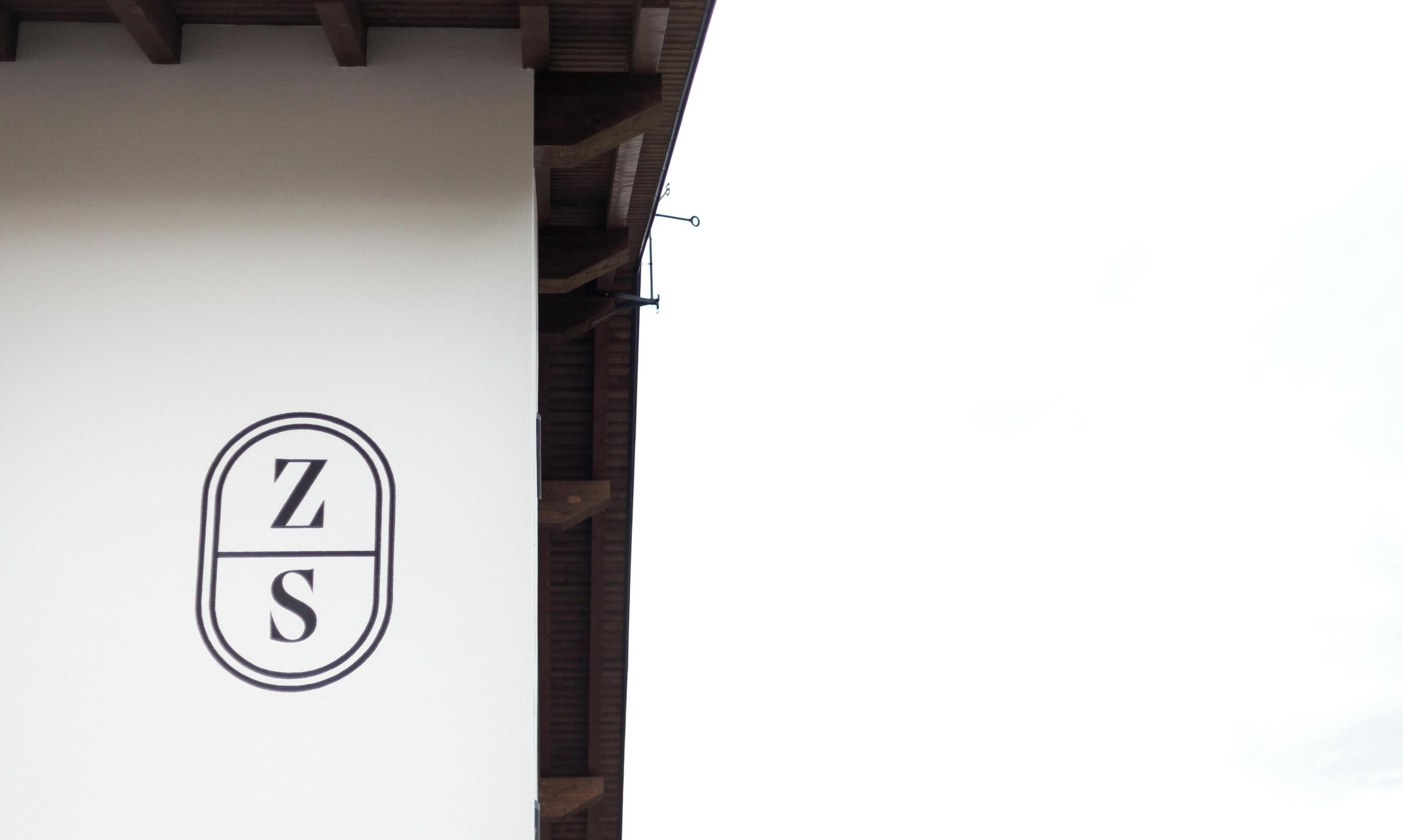 Ein Gebäude mit weißer Fassade und einem Logo, das die Buchstaben 'Z' und 'S' in einem Kreis zeigt.