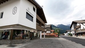A building with a sign reading 'Zum Sonnentor' and a mountain backdrop. - Apartment 'Zum Sonnentor - Larix' with Mountain View, Balcony & Wi-Fi (Luttach)