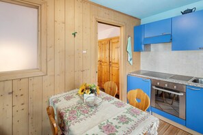 Una cocina con paredes de madera, un armario azul, una estufa y una mesa con mantel floreado.