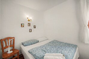 A bedroom with a bed, a chair, a wall-mounted light, and several framed pictures. - Apartment 'Sea Breeze' with Terrace, Shared Garden & Wi-Fi (Vilanova i la Geltrú)