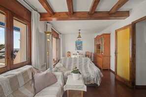Ein Zimmer mit Holzboden, einem Esstisch für zwei Personen, einer Couch und einem Schrank.