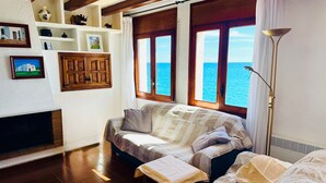 Una sala de estar acogedora con un sofá, chimenea, vista al mar y una lámpara.