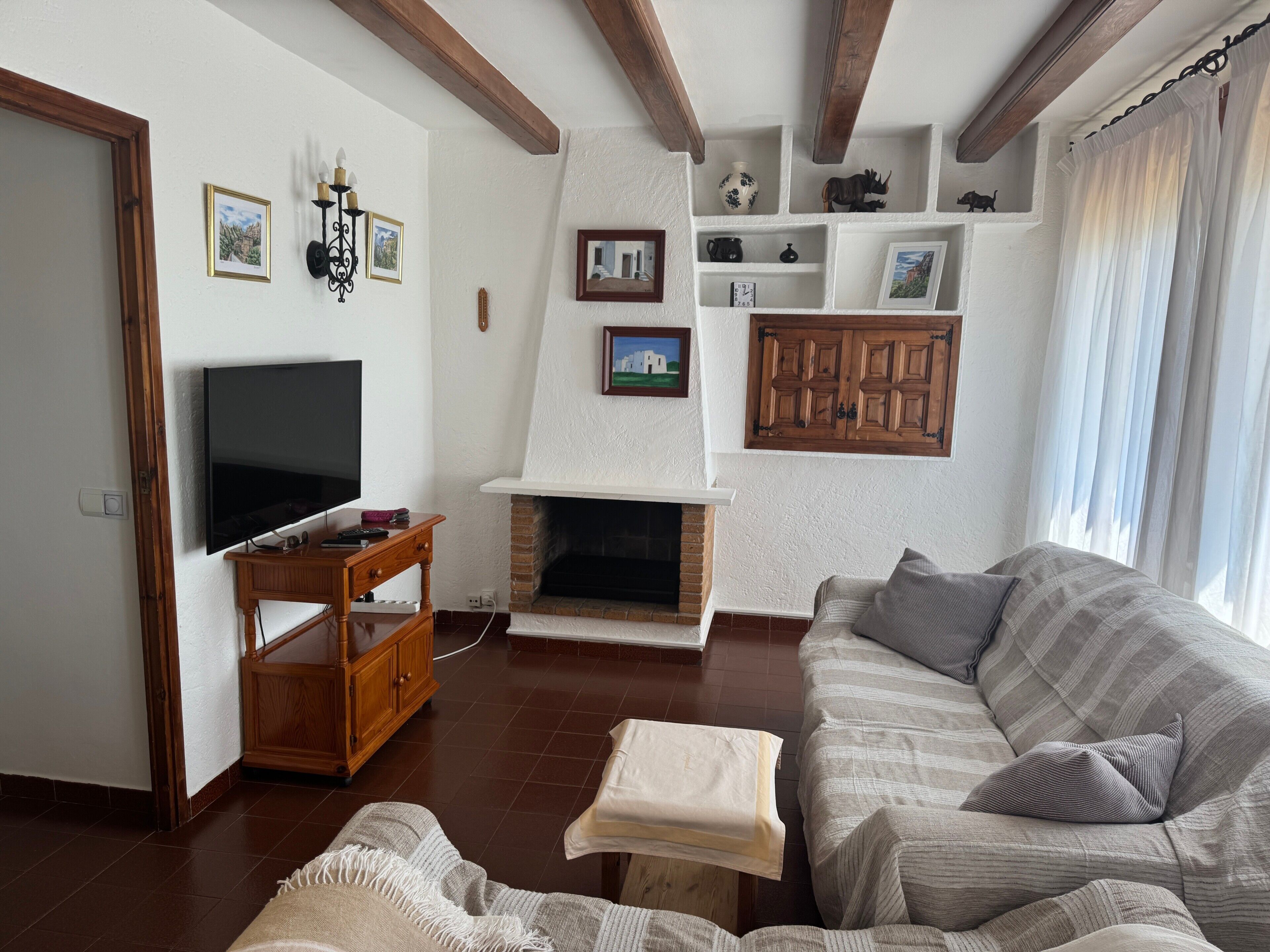 A living room with a fireplace, a television, a sofa, and a wooden cabinet.