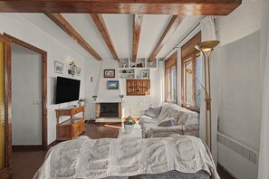 A cozy living room with a fireplace, a television, and a sofa. - Apartment 'Sea Breeze' with Terrace, Shared Garden & Wi-Fi (Vilanova i la Geltrú)