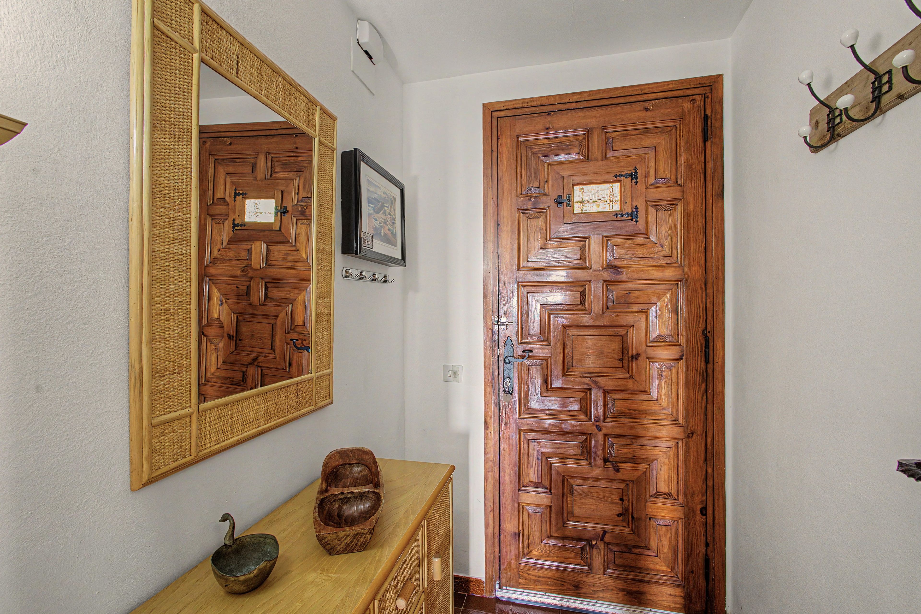 A wooden door with a geometric pattern, a large mirror, and a small decorative bowl on a wooden dresser.
