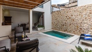 A modern outdoor space with a pool, seating, and a stone wall. - Vacation Home 'Casa Bugera' with Pool, Balcony, A/C & Wi-Fi (Pollenca)