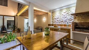 A modern kitchen with a stone backsplash, a built-in oven, and a dining area with a wooden table and chairs. - Vacation Home 'Casa Bugera' with Pool, Balcony, A/C & Wi-Fi (Pollenca)