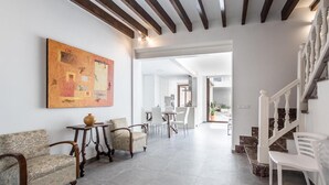 A spacious living area with a dining table, chairs, a coffee table, and a painting on the wall. - Vacation Home 'Casa Bugera' with Pool, Balcony, A/C & Wi-Fi (Pollenca)