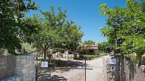 A gated entrance to a property with a stone wall, a metal gate, and a sign indicating 'Villa Plus Burgos.' - Finca Villa Burgues with Mountain View, Pool, Garden, Terrace & Wi-Fi (Alcudia)