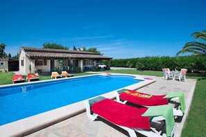 Une piscine avec des chaises longues, un patio couvert et une maison avec un toit en tuiles.