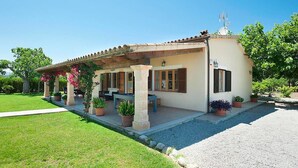 A two-story house with a covered patio, a satellite dish, and a garden with potted plants. - Finca Villa Burgues with Mountain View, Pool, Garden, Terrace & Wi-Fi (Alcudia)