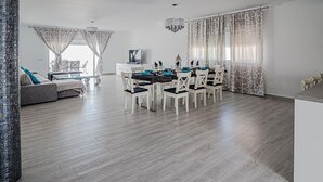 A spacious living area with a dining table set for six, a sofa, and a TV. - Casa Rural "Villa MyJ" with Pool, Garden, Terrace & Wi-Fi (La Puebla de Cazalla)