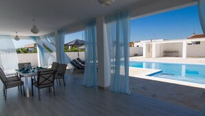 A spacious room with a dining area, a pool, and large windows with sheer curtains. - Casa Rural "Villa MyJ" with Pool, Garden, Terrace & Wi-Fi (La Puebla de Cazalla)