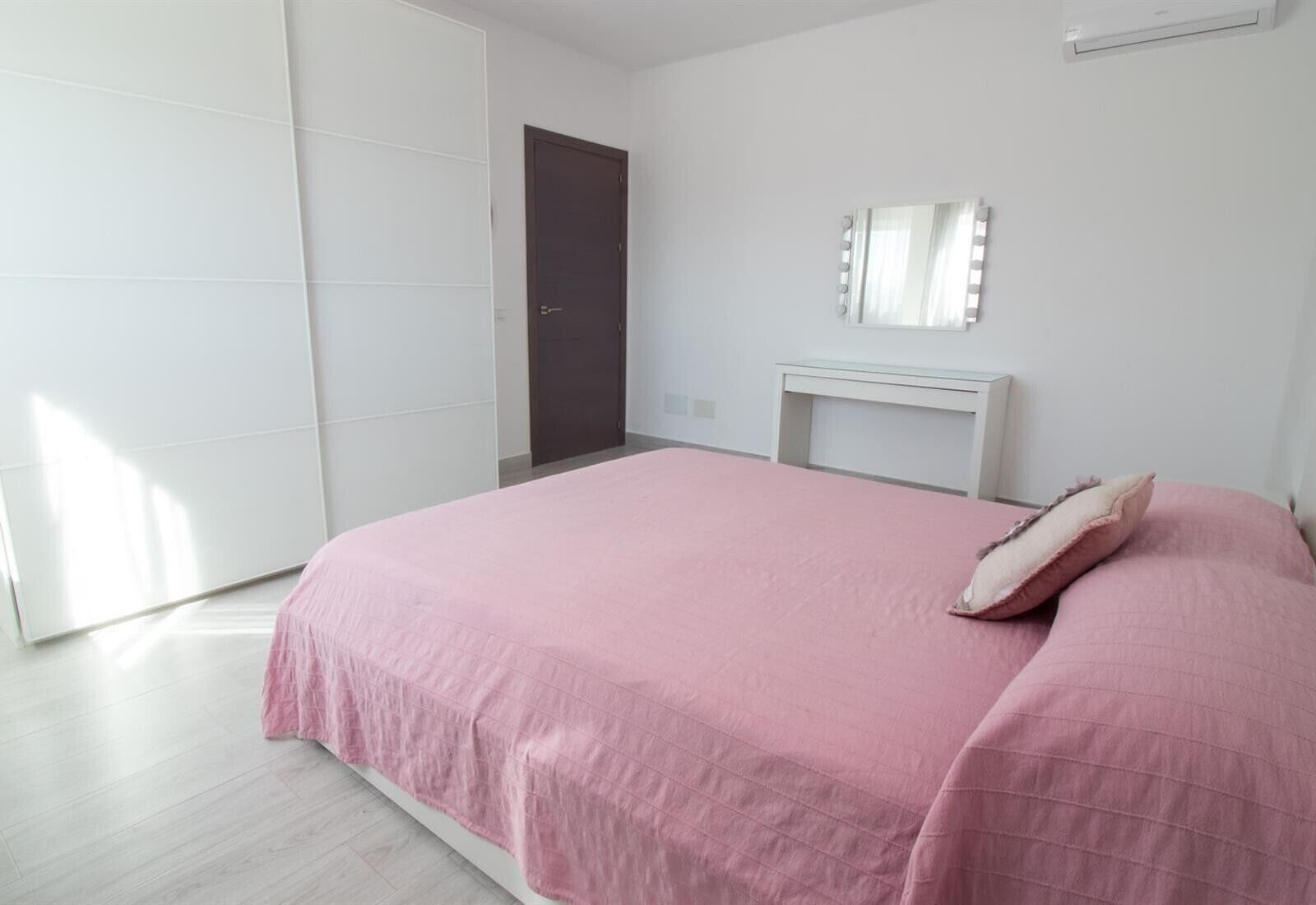 Un dormitorio con cama, mesita de noche, espejo y armario.