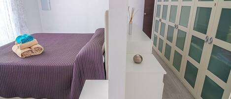 A room with a bed, a small table with a vase, and a wardrobe with glass doors.