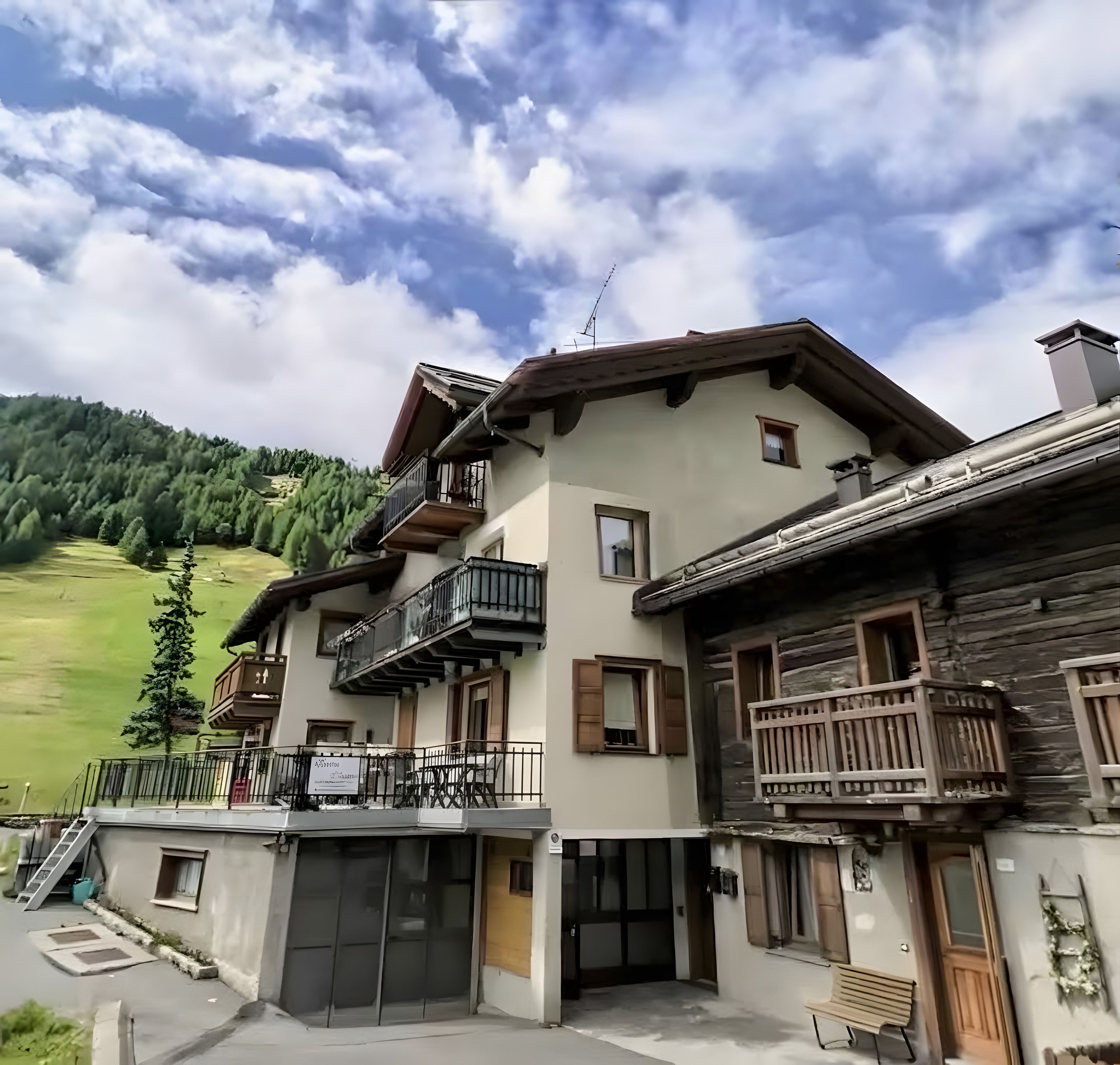 Un edificio de varios pisos con balcones, fachada de madera y vistas a una ladera verde.