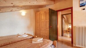 Camera da letto con due letti, un armadio in legno e un termosifone.