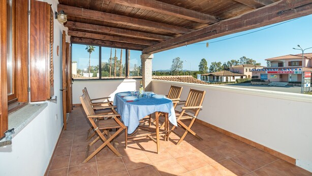 An outdoor patio with a table and chairs, a wooden ceiling, and a view of the surrounding area. - Holiday Home 'Trilocale con Ampia Veranda Mare' with A/C & Terrace (san teodoro)