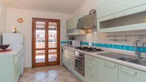 A kitchen with a gas stove, oven, microwave, and a sink. - Holiday Home 'Trilocale con Ampia Veranda Mare' with A/C & Terrace (san teodoro)