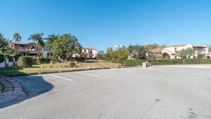 A parking lot with a clear sky, palm trees, and residential buildings in the background. - Holiday Home 'Trilocale con Ampia Veranda Mare' with A/C & Terrace (san teodoro)