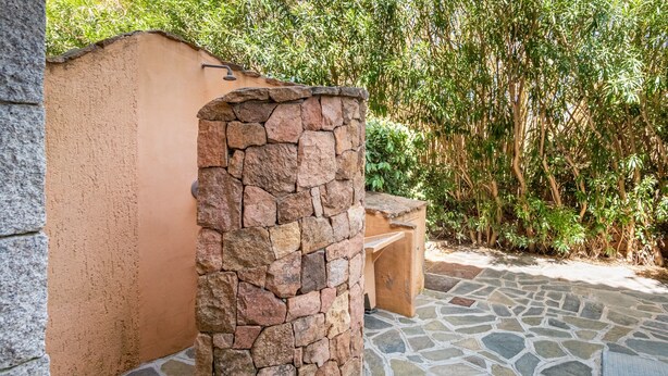 Un pilar de piedra, un banco de madera y un suelo de losas de piedra.