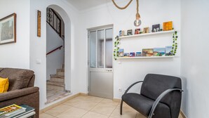 A living room with a sofa, a chair, a staircase, and a door leading to another room. - Pet-friendly holiday home 'Casa Quintião' with Wi-Fi (Ferragudo)