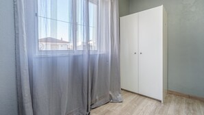 A room with a large window, sheer curtains, a white wardrobe, and a light-colored floor. - Pet-friendly holiday home 'Casa Quintião' with Wi-Fi (Ferragudo)