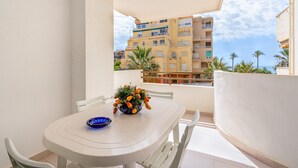 Un balcón con una mesa, sillas, un cuenco azul y un arreglo floral.