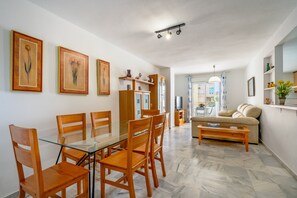 Un coin repas avec une table en verre et des chaises en bois, un canapé et une table basse.