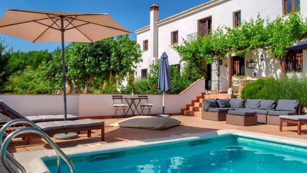 Un espace piscine aménagé avec des chaises longues, une table et des parasols.