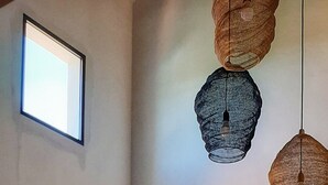 Un salon avec un canapé, deux fauteuils, une lampe et des luminaires suspendus.