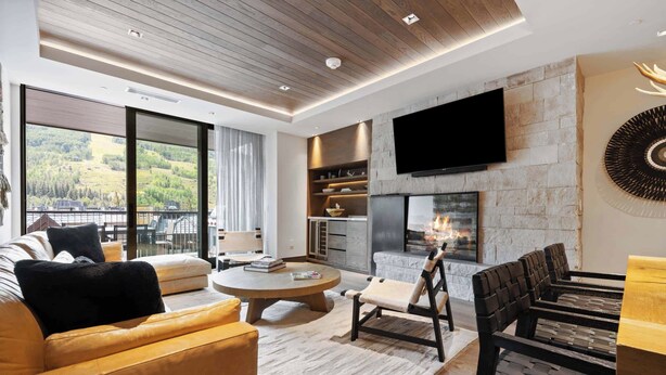 Una sala de estar moderna con chimenea, sofás de cuero, una mesa de centro redonda y un televisor montado en la pared.