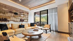 Una sala de estar moderna con un sofá modular grande, una mesa de centro redonda y vistas al exterior a través de amplios ventanales.