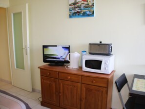 Compact kitchenette with a flat-screen TV, microwave, and ample storage.