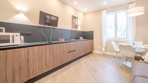 A modern kitchen with a built-in microwave, a flat-screen TV, and a dining area with a table and chairs. - GuestHost - Comfortable 40 sqm apartment perfect for 4 guests is located in the heart of the most authentic Genoese historic center, a few steps from Piazza delle Vigne and the church of the same name with the beautiful bell tower that stands out over th (Genova)