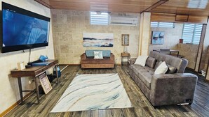 A modern living room with a flat-screen TV, a brown sofa, a gray sofa, a wooden coffee table, and a large abstract rug. - Casa Oceana Minutes to Seven Seas Beach + Bio Bay + Marinas (Fajardo)