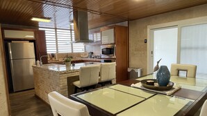 A modern kitchen with a central island, stainless steel appliances, and a dining area with a glass table and chairs. - Casa Oceana Minutes to Seven Seas Beach + Bio Bay + Marinas (Fajardo)