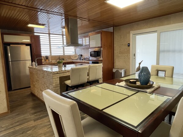 A modern kitchen with a central island, stainless steel appliances, and a dining area with a glass table and chairs.