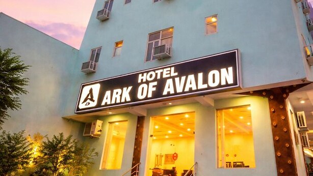 A hotel named 'ARK OF AVALON' with a light blue facade, multiple windows, and a visible entrance with steps.