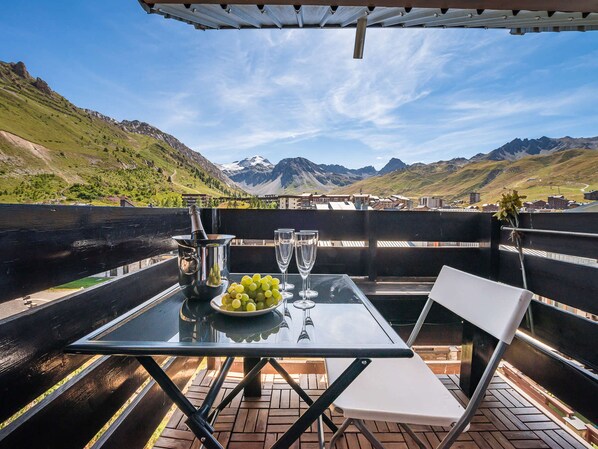A table with a bottle, a bowl of grapes, and two glasses on a terrace with a mountain view. - Premium Triplex in Tignes-Le Lavachet for 6 people with south-facing balcony (Tignes-Le Lavachet)