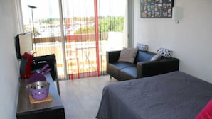 Une chambre d’hôtel avec un lit, un bureau, une chaise et un balcon donnant sur l’extérieur.
