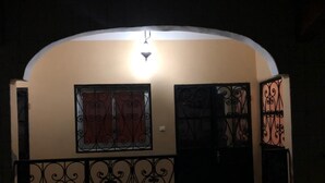 En välvd entré med dekorativa järngaller, en lampa ovanför och en dörr med ett fönster.