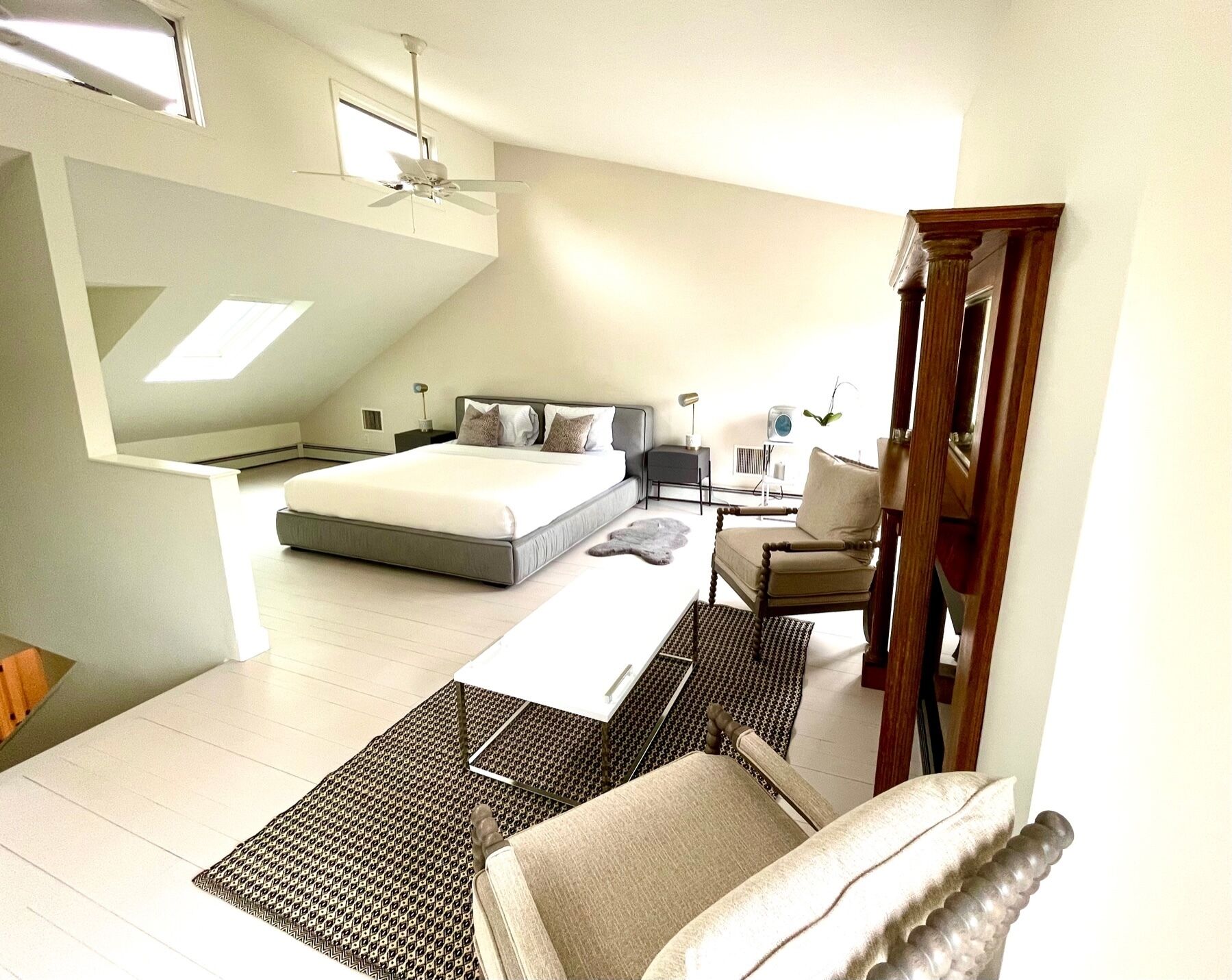 A modern bedroom with a large bed, a desk, a chair, and a ceiling fan.