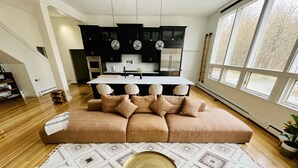 Una sala de estar moderna con un amplio sofá seccional color beige, una mesa redonda de centro y una alfombra estampada.