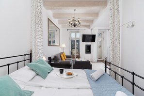 Une chambre à coucher moderne avec un lit, un canapé, une télévision et une cheminée.