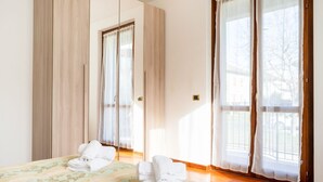 Ein Hotelzimmer mit einem Bett, einem Kleiderschrank und einem großen Fenster mit Vorhängen.