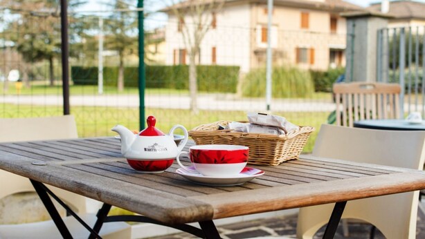 Ein Holztisch mit Teekanne und Tasse, ein Korbwägelchen und Blick auf eine Wohngegend.