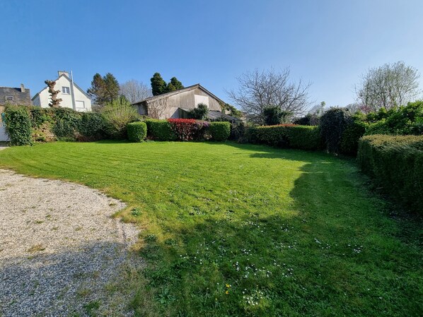 A well-maintained lawn with a gravel path leading to a house with a stone facade and a chimney.