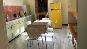 A kitchen with a dining table, chairs, a yellow refrigerator, and a tiled floor. - QUIET STONE HOUSE 3KMS FROM THE BEACH (La Foret-Fouesnant)
